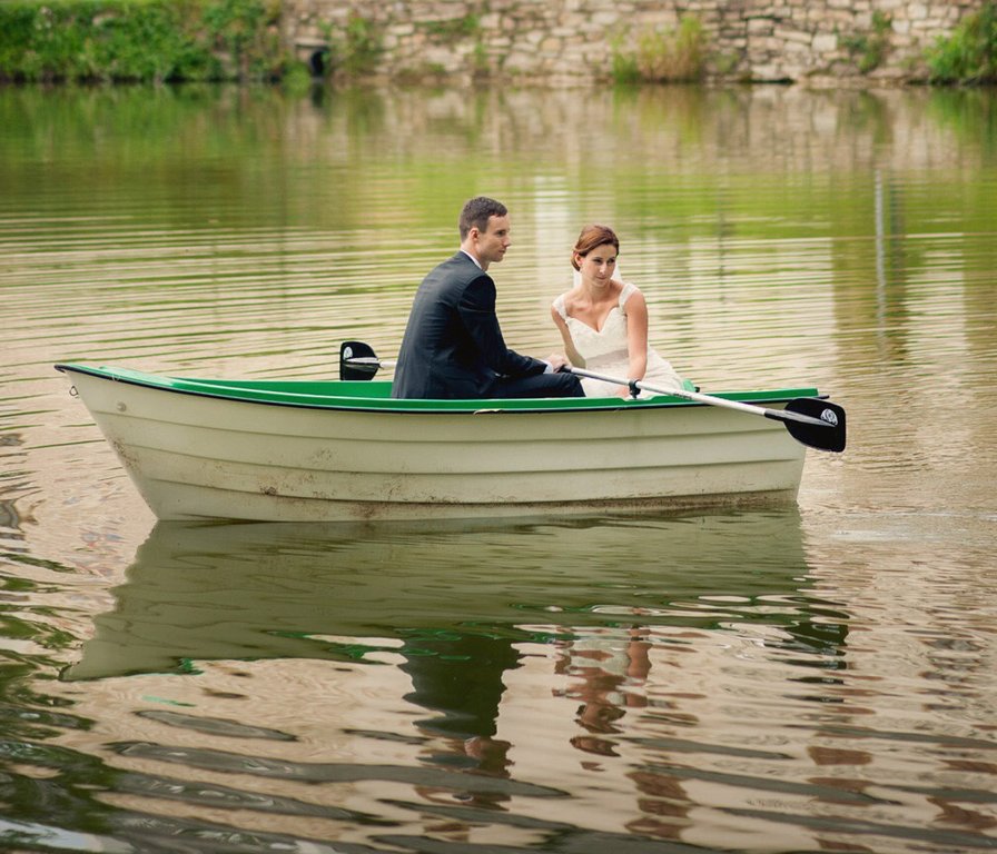 Novomanželé na loďce na hladině rybníka